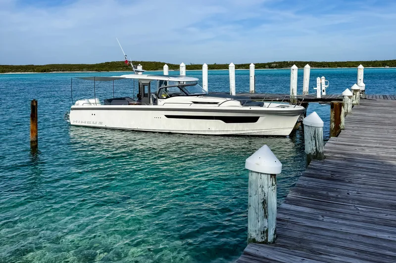 Slide: The Image of 2023 Nimbus Tender 11 docked by a wooden pier in clear turquoise water. - 2