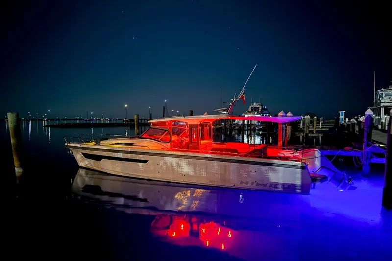 Slide: The Image of 2023 Nimbus Tender 11 boat illuminated at night in a marina setting. - 22