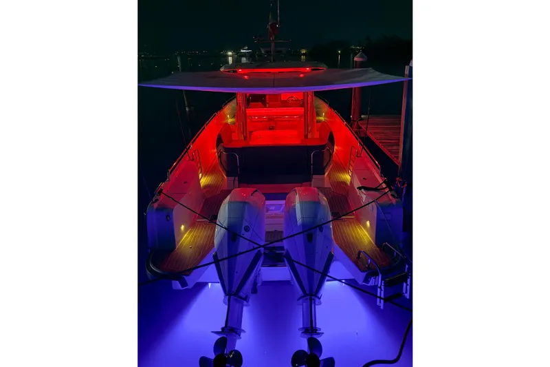 Slide: The Image of 2023 Nimbus Tender 11 boat illuminated with vibrant red and blue lights at night. - 23