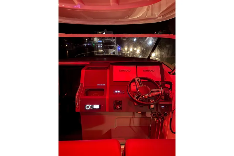 Slide: The Image of Cockpit of 2023 Nimbus Tender 11 boat illuminated in red light at night. - 25