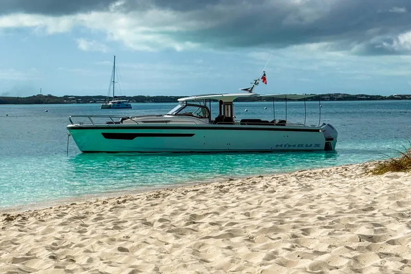 Slide: The Image of 2023 Nimbus Tender 11 boat anchored near sandy beach, turquoise water, and cloudy sky. - 35