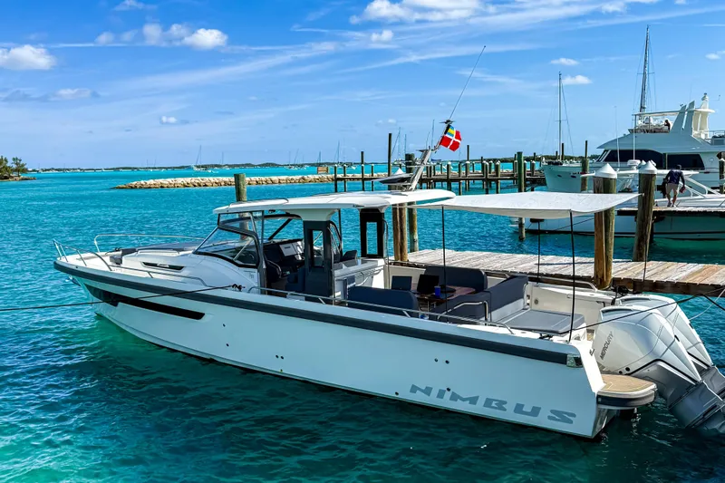 Slide: The Image of 2023 Nimbus Tender 11 boat docked in a vibrant turquoise marina. - 4
