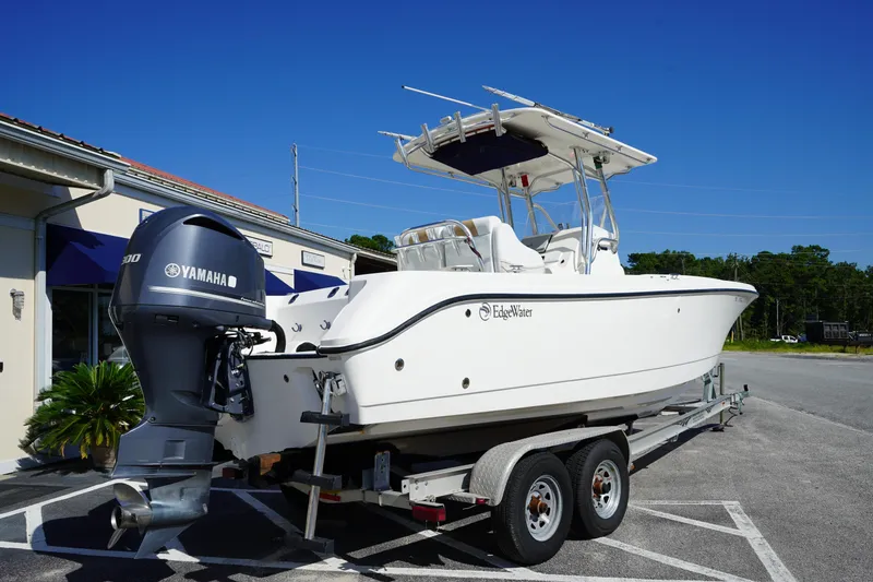 Slide: The Image of 2014 Edgewater 245CC boat on trailer with Yamaha outboard motor, parked outdoors. - 2