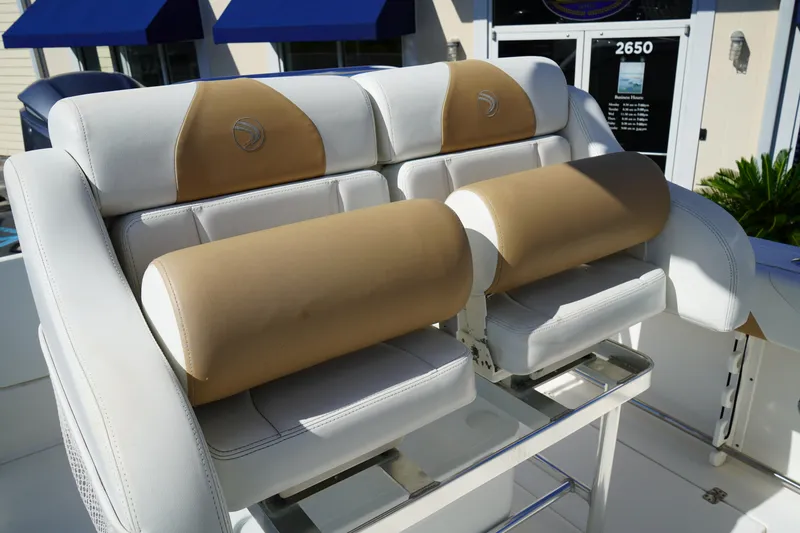 Slide: The Image of 2014 Edgewater 245CC boat seats with tan and white upholstery, outdoor setting. - 24