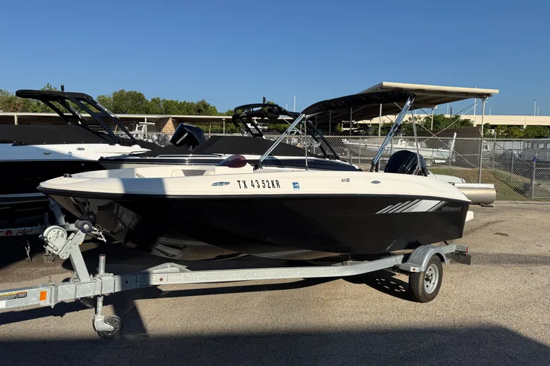 Slide: The Image of 2023 Bayliner Element E18 boat on trailer, parked outdoors under clear sky. - 13