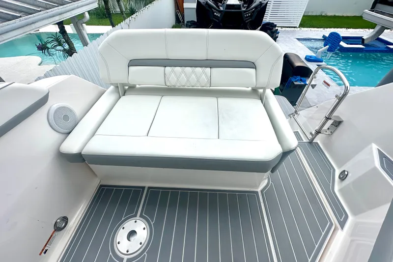 Slide: The Image of 2025 Regal 26 XO boat with white cushioned seating and gray deck near a pool. - 28