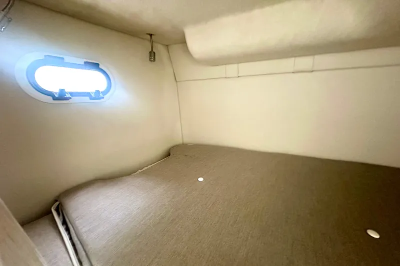 Slide: The Image of 2025 Regal 26 XO cabin interior with bed and porthole window. - 52