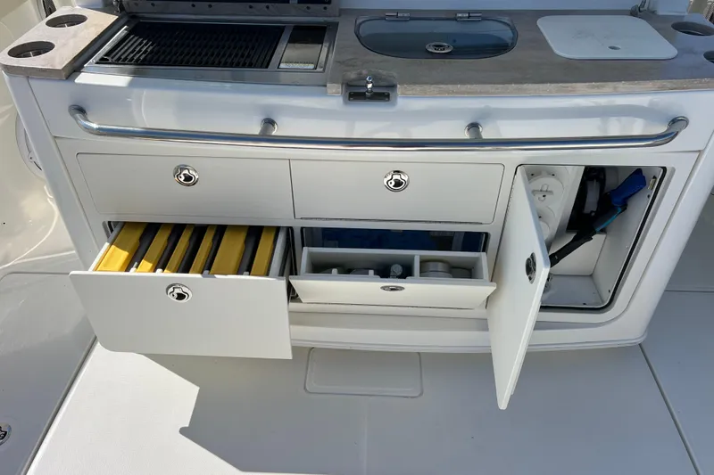 Slide: The Image of 2019 Boston Whaler 380 Outrage storage compartments with grill and sink. - 13