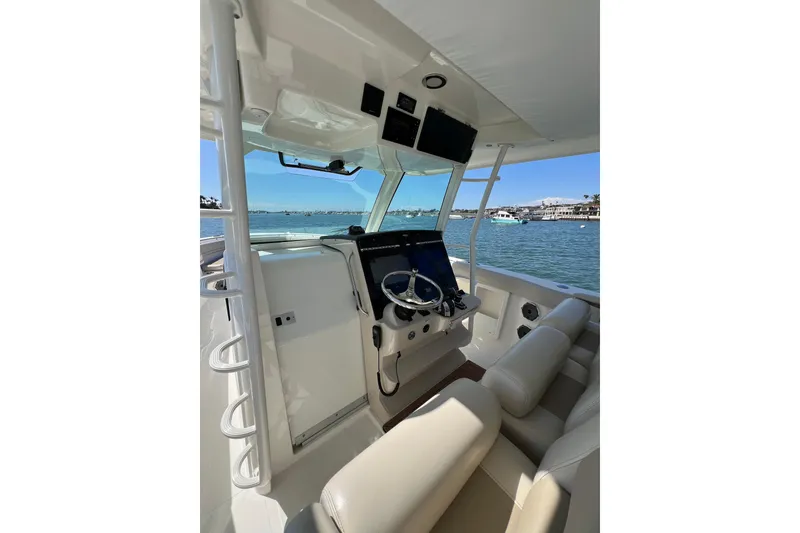 Slide: The Image of 2019 Boston Whaler 380 Outrage helm with modern controls, overlooking a scenic waterfront. - 14