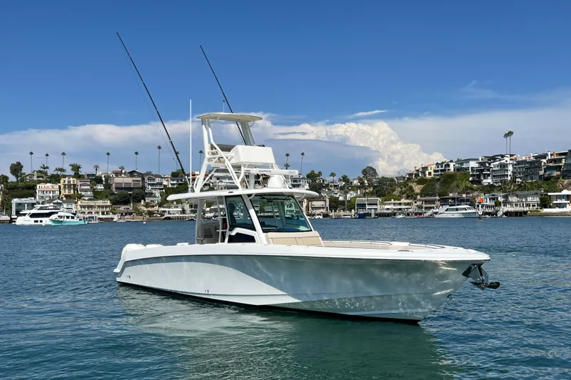 Slide: The Image of 2019 Boston Whaler 380 Outrage boat on calm water with coastal homes in the background. - 20