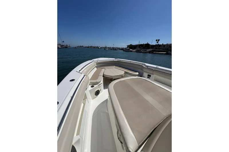 Slide: The Image of 2019 Boston Whaler 380 Outrage boat interior with cushioned seating, docked in a marina. - 3
