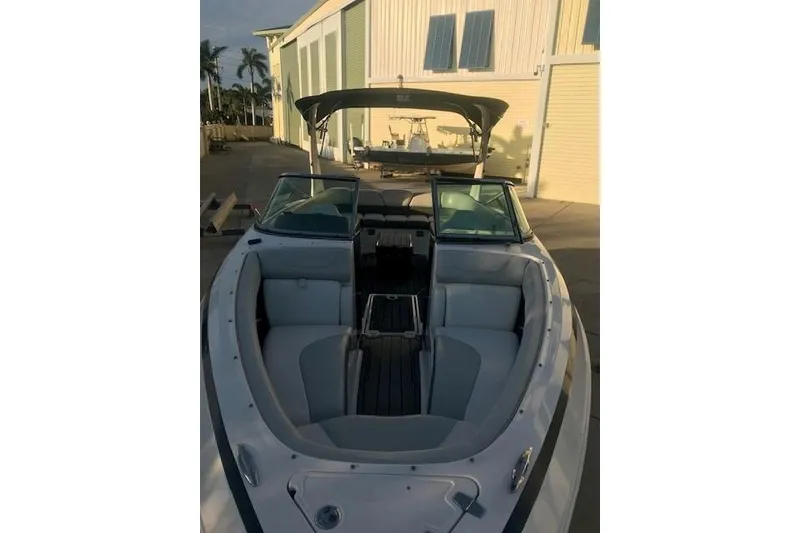 Slide: The Image of 2012 Regal 2500 Bowrider boat with open seating, docked near a building. - 10