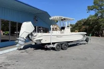 Slide: The Image of 2026 Ranger 2660 Bay boat on trailer outside blue building under clear sky. - 2