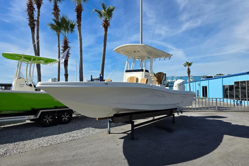 Slide: The Image of 2026 Ranger 2660 Bay boat on trailer, parked outside a blue building with palm trees. - 5