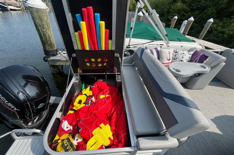 Slide: The Image of 2021 Bennington 21 SSBX pontoon boat with storage open, showing pool noodles and gear. - 10