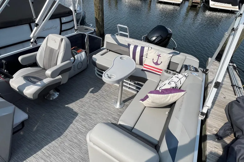 Slide: The Image of 2021 Bennington 21 SSBX pontoon boat interior with plush seating and nautical-themed pillows. - 17