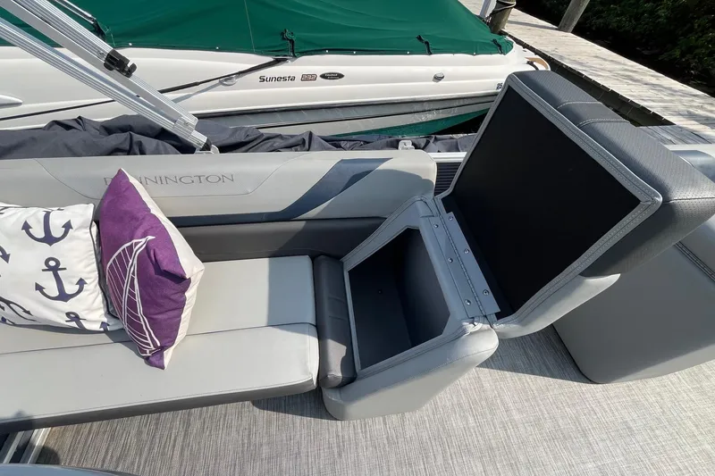 Slide: The Image of 2021 Bennington 21 SSBX boat interior with open storage compartment and nautical-themed cushions. - 19