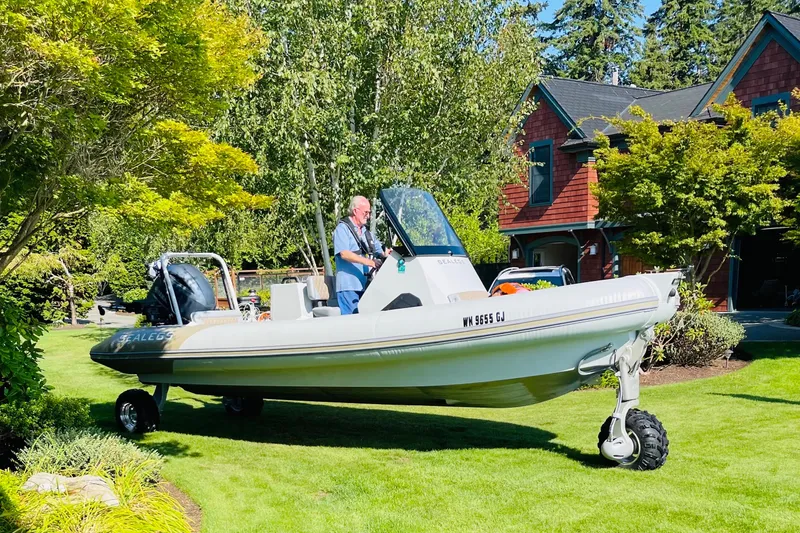 Slide: The Image of 2022 Sealegs 7.5M amphibious boat on grass, near a house and trees. - 3