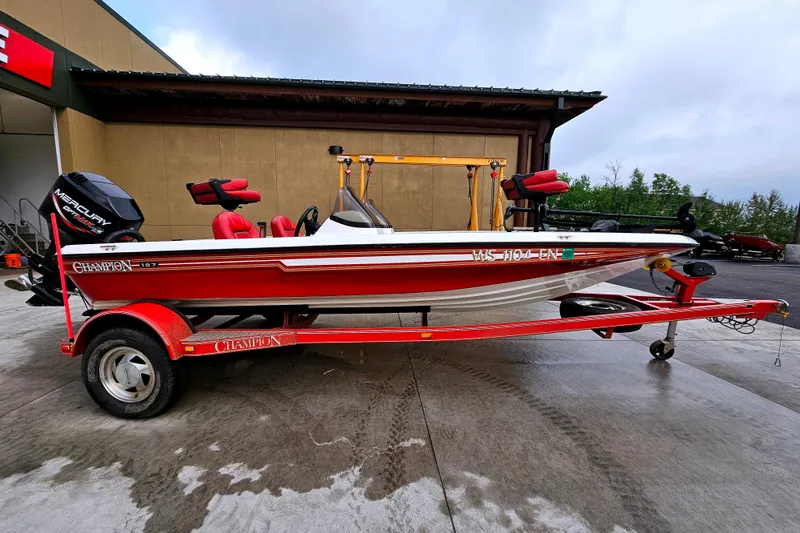 Slide: The Image of 1998 Champion 187 DLX Elite boat with red trailer, parked outdoors. - 0