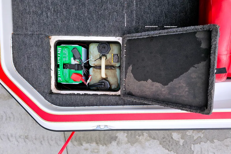 Slide: The Image of Open compartment in 1998 Champion 187 DLX Elite boat showing battery and fuel tank. - 13