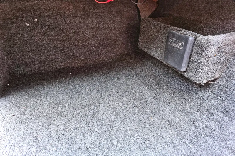Slide: The Image of Carpeted interior of a 1998 Champion 187 DLX Elite boat, featuring a storage compartment. - 25