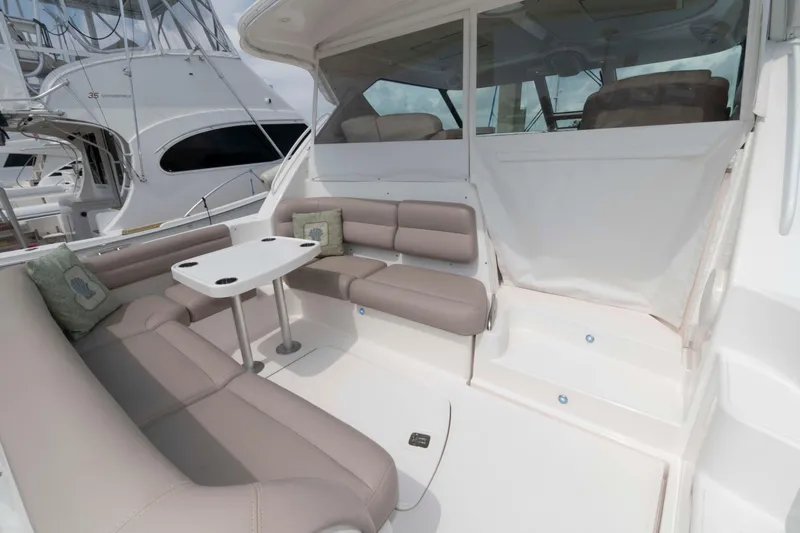 Slide: The Image of 2007 Tiara Yachts 4300 Sovran cockpit with beige seating and table, docked at marina. - 3
