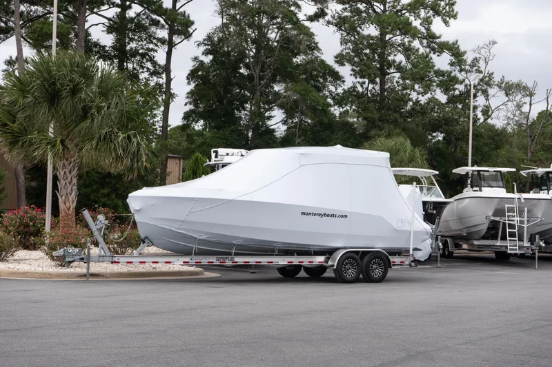 The Image of 2026 Monterey Elite 27 OB boat covered on a trailer in a parking lot. - 0