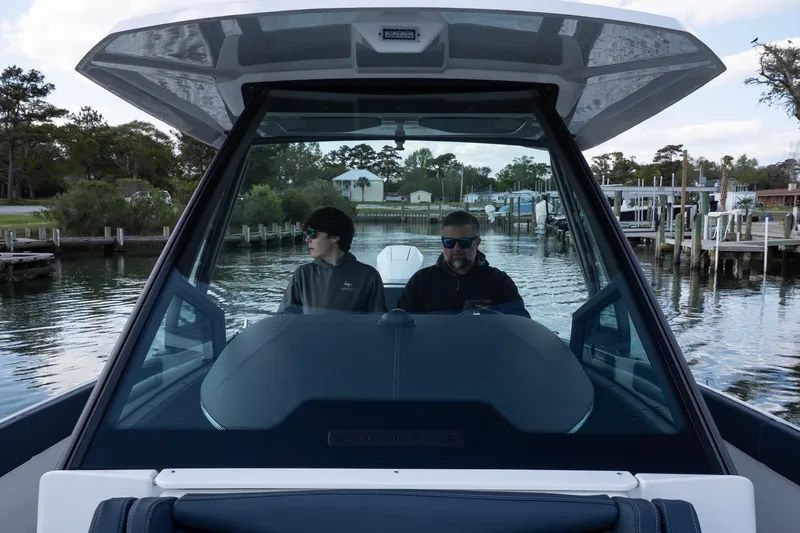 Slide: The Image of 2026 Monterey Elite 27 OB boat with two people navigating through a calm marina. - 15