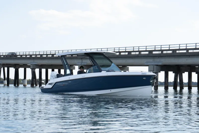 Slide: The Image of 2026 Monterey Elite 27 OB boat on water near a bridge, showcasing sleek design. - 7