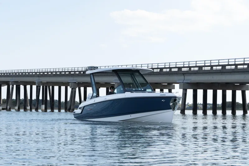 Slide: The Image of 2026 Monterey Elite 27 OB boat cruising near a bridge on calm waters. - 8