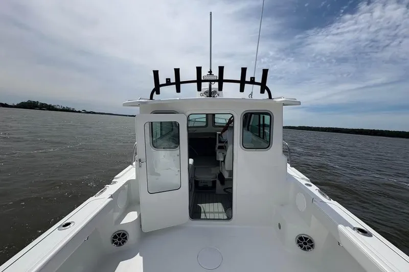 Slide: The Image of 2026 Parker 2420 Sport Cabin boat on open water under a partly cloudy sky. - 10