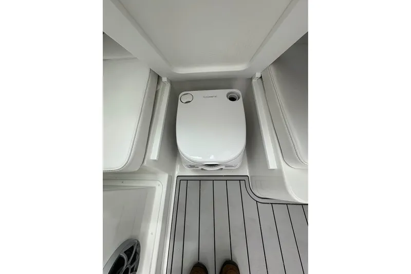 Slide: The Image of 2026 Parker 2420 Sport Cabin interior with compact marine toilet and cushioned seating. - 6
