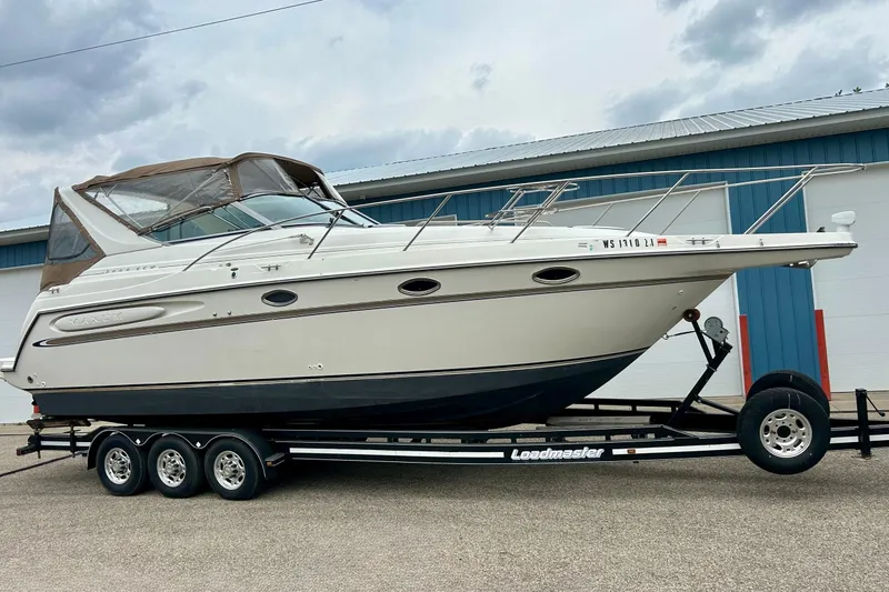The Image of 2000 Maxum 3000 SCR boat on Loadmaster trailer, parked outdoors. - 0