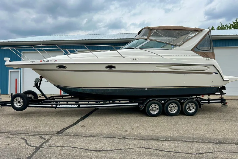 Slide: The Image of 2000 Maxum 3000 SCR boat on trailer, parked outdoors near a blue building. - 1