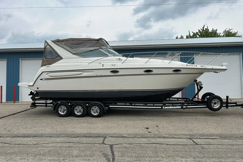 Slide: The Image of 2000 Maxum 3000 SCR boat on trailer, parked outside blue building. - 32