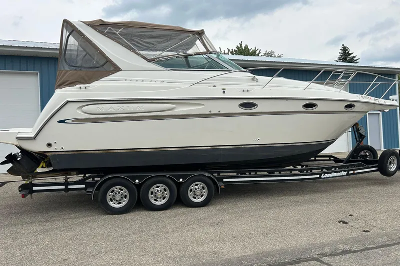 Slide: The Image of 2000 Maxum 3000 SCR boat on trailer, parked outdoors near blue building. - 33