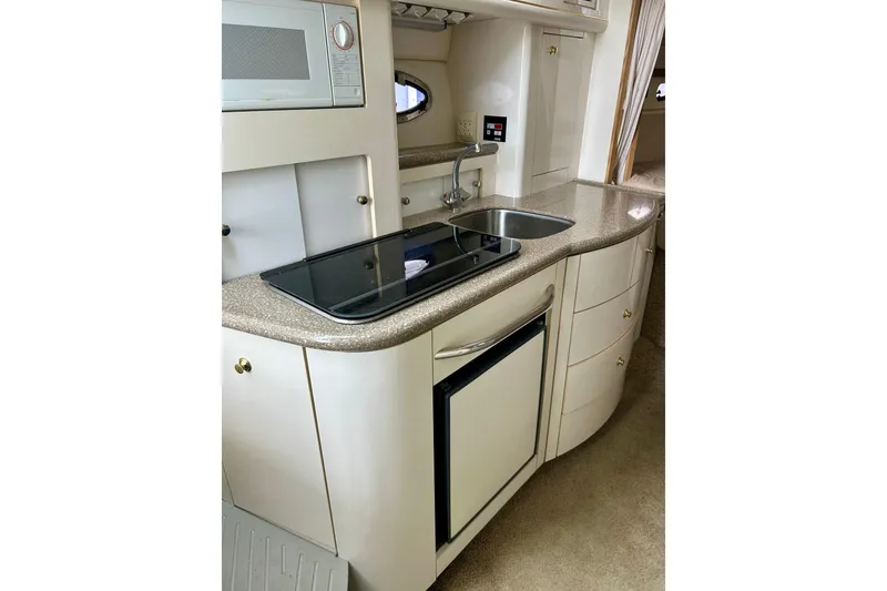 Slide: The Image of 2000 Maxum 3000 SCR boat kitchen with sink, stove, and compact fridge. - 8