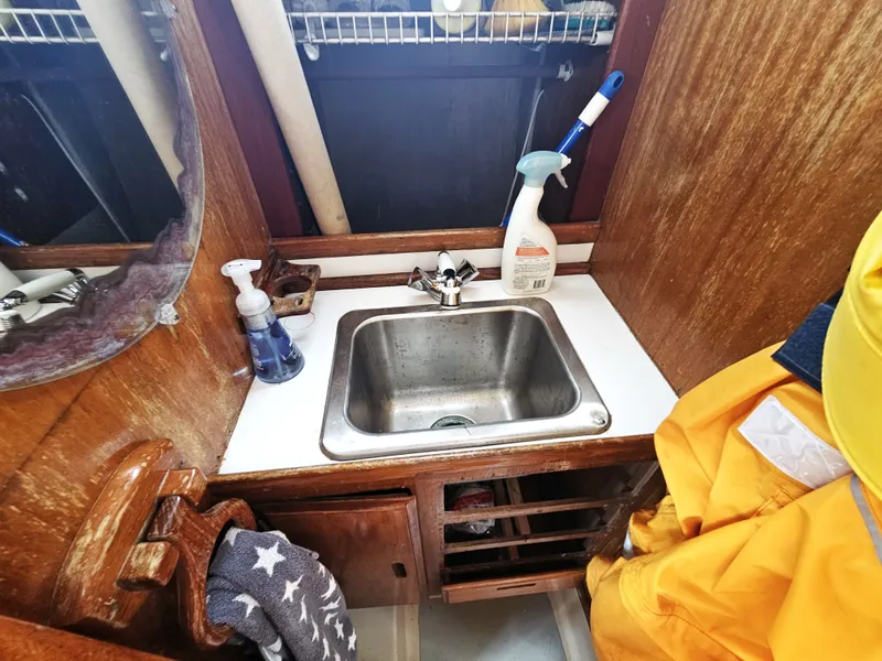 Slide: The Image of 1967 Jensen Cal 36 boat interior with sink, cleaning supplies, and wooden cabinetry. - 21