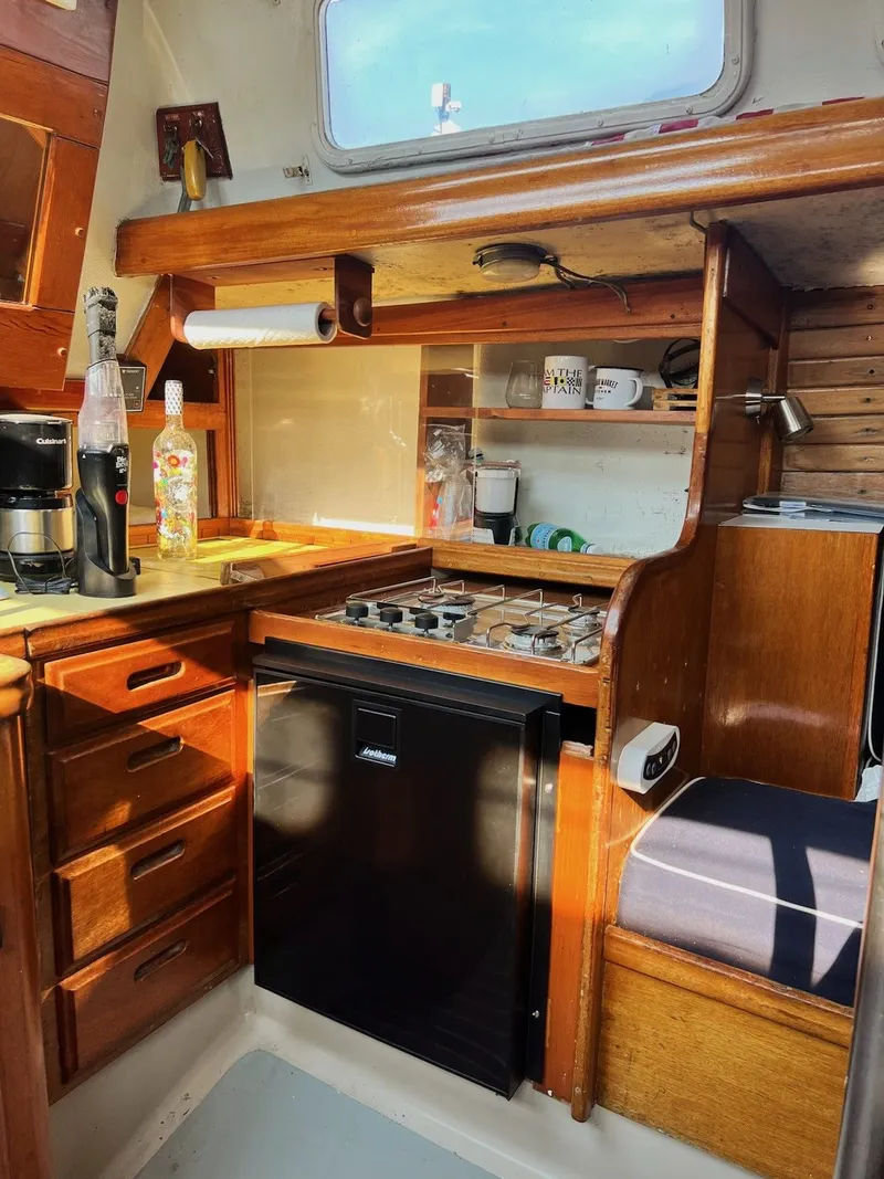 Slide: The Image of 1967 Jensen Cal 36 yacht kitchen with wooden cabinets, stove, and compact fridge. - 30