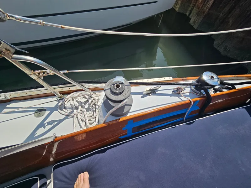 Slide: The Image of 1967 Jensen Cal 36 sailboat deck with winch, ropes, and railing in sunlight. - 11