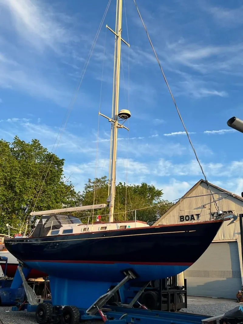 Slide: The Image of 1967 Jensen Cal 36 sailboat on trailer, blue sky background, near boatyard. - 34