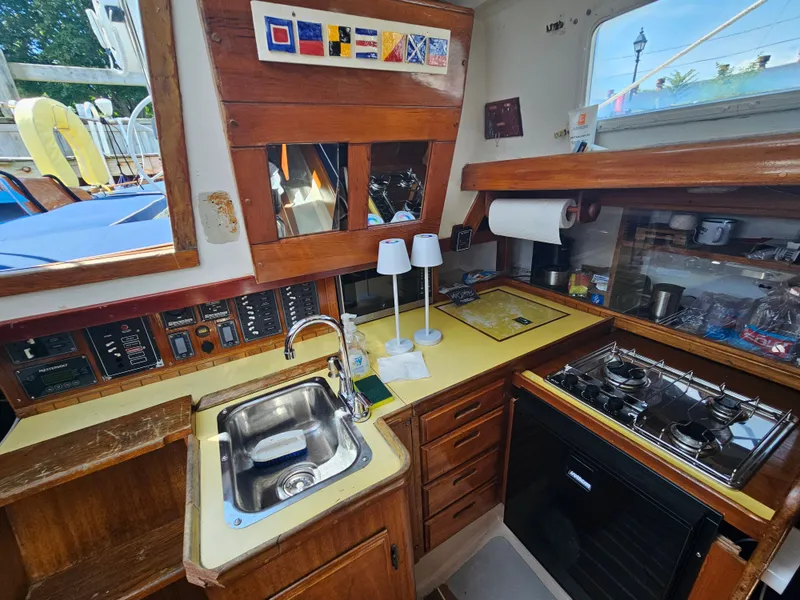 Slide: The Image of 1967 Jensen Cal 36 yacht kitchen with sink, stove, and wooden cabinetry. - 29