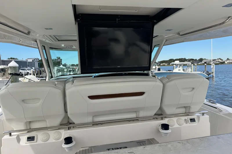 Slide: The Image of 2023 Tiara Yachts 43 LS interior with TV, luxurious seating, and marina view. - 42