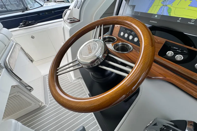Slide: The Image of 2023 Tiara Yachts 43 LS helm with wooden steering wheel and navigation display. - 52