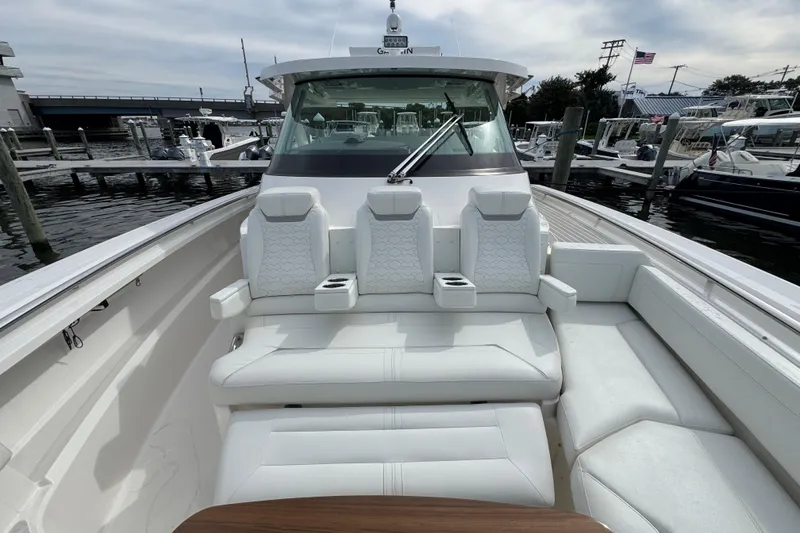 Slide: The Image of 2023 Tiara Yachts 43 LS luxury boat interior with white seating and dock view. - 61