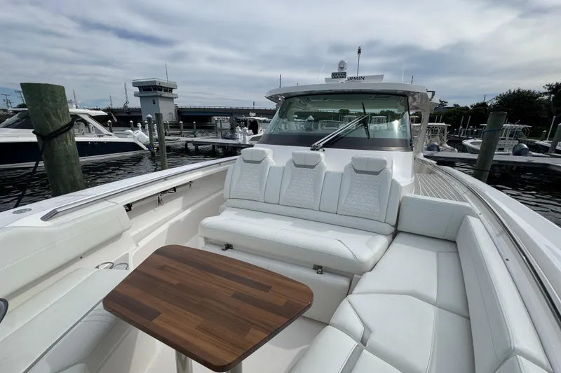 Slide: The Image of 2023 Tiara Yachts 43 LS luxury boat with white seating and wooden table at marina. - 64