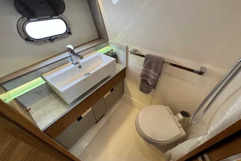 Slide: The Image of 2023 Tiara Yachts 43 LS bathroom with modern sink, toilet, and porthole window. - 78