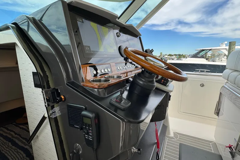 Slide: The Image of 2023 Tiara Yachts 43 LS helm with modern navigation system and wooden steering wheel. - 81