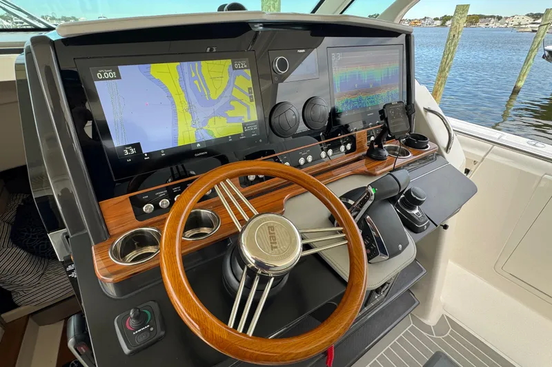 Slide: The Image of 2023 Tiara Yachts 43 LS helm with advanced navigation displays and wooden steering wheel. - 82