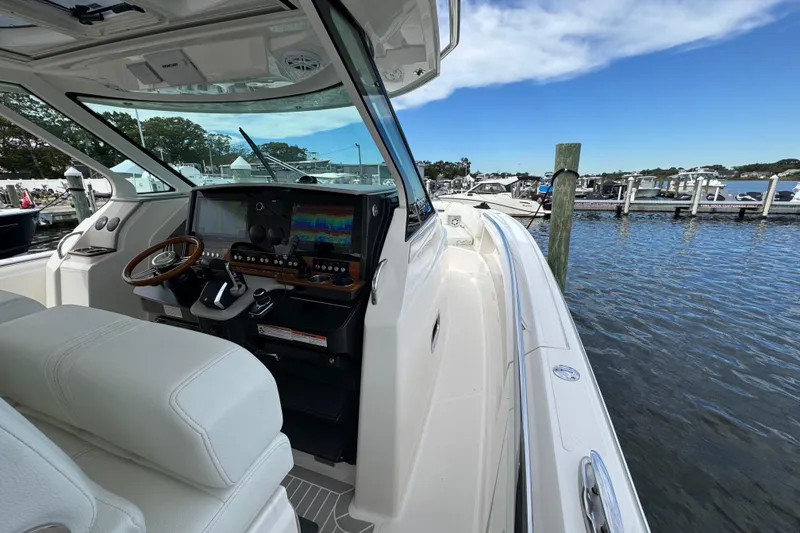 Slide: The Image of 2023 Tiara Yachts 43 LS helm with modern controls, docked at marina. - 97